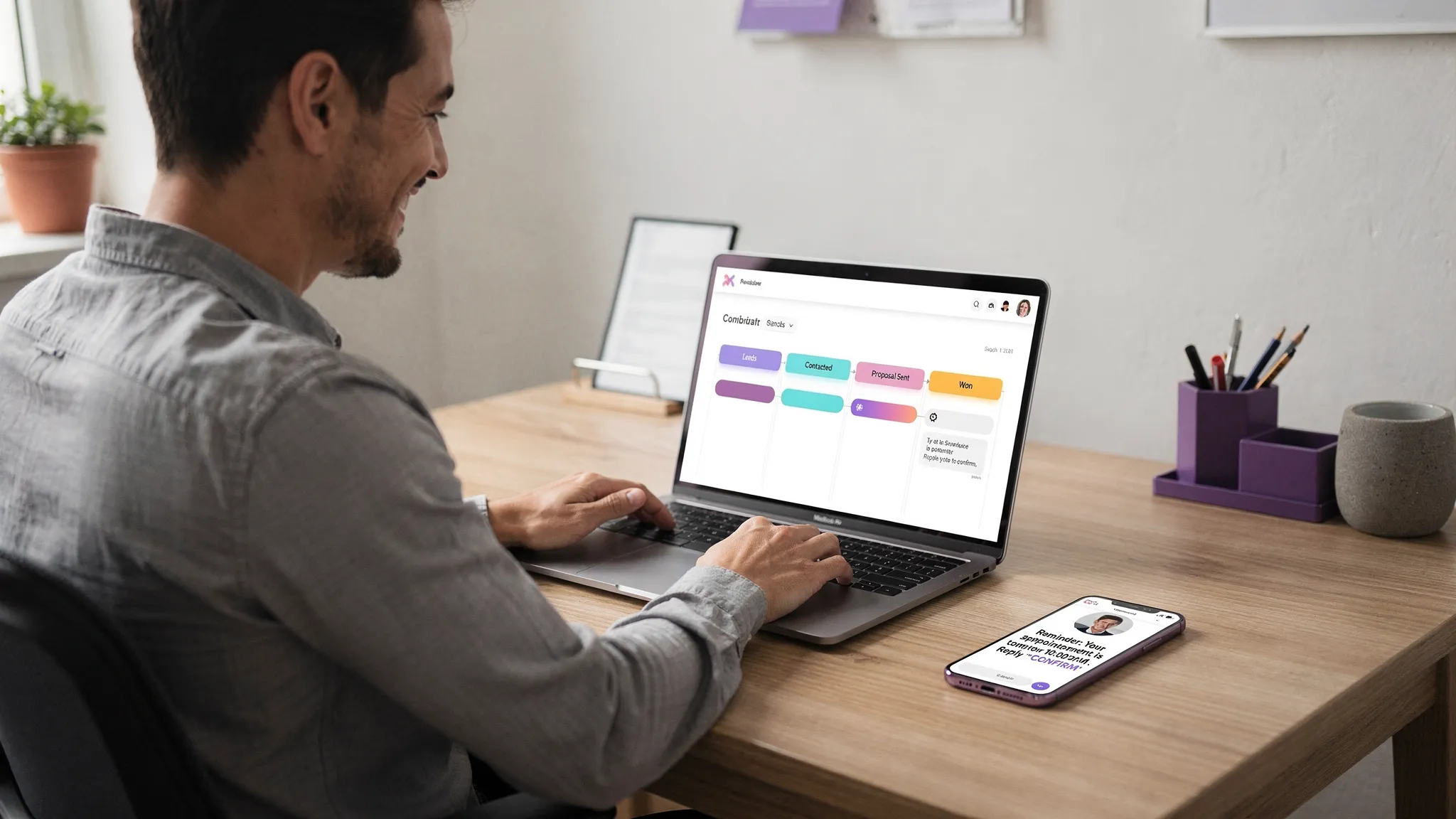 A small business owner in a local office reviewing a simple CRM pipeline on a laptop, with a phone showing an automated appointment reminder message, illustrating “do more with less” through automation.